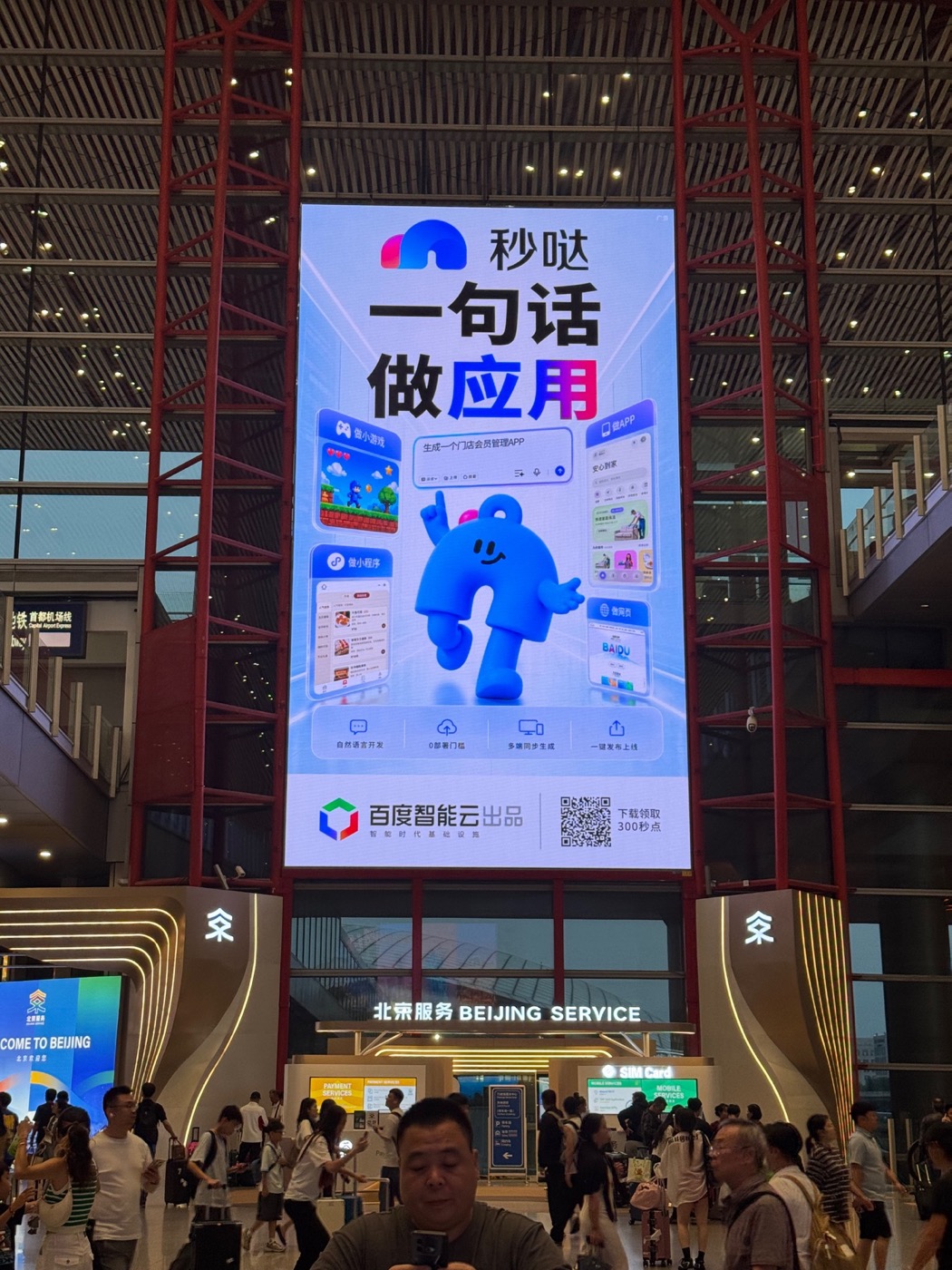 A large advertisement at Beijing Capital International Airport promising that one sentence can make an app