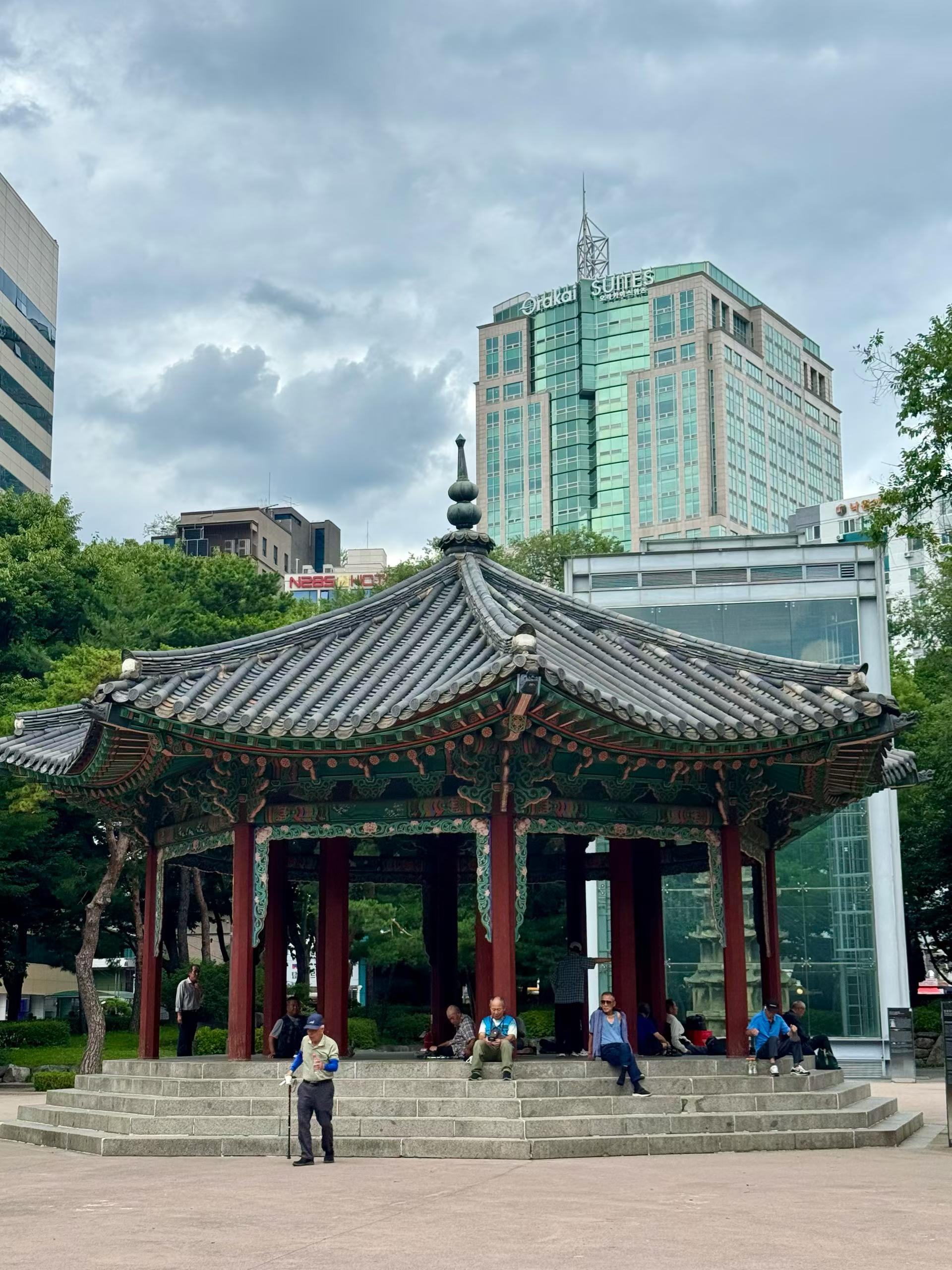 Older people gathered around a traditional pavilion near Jongno 3-ga