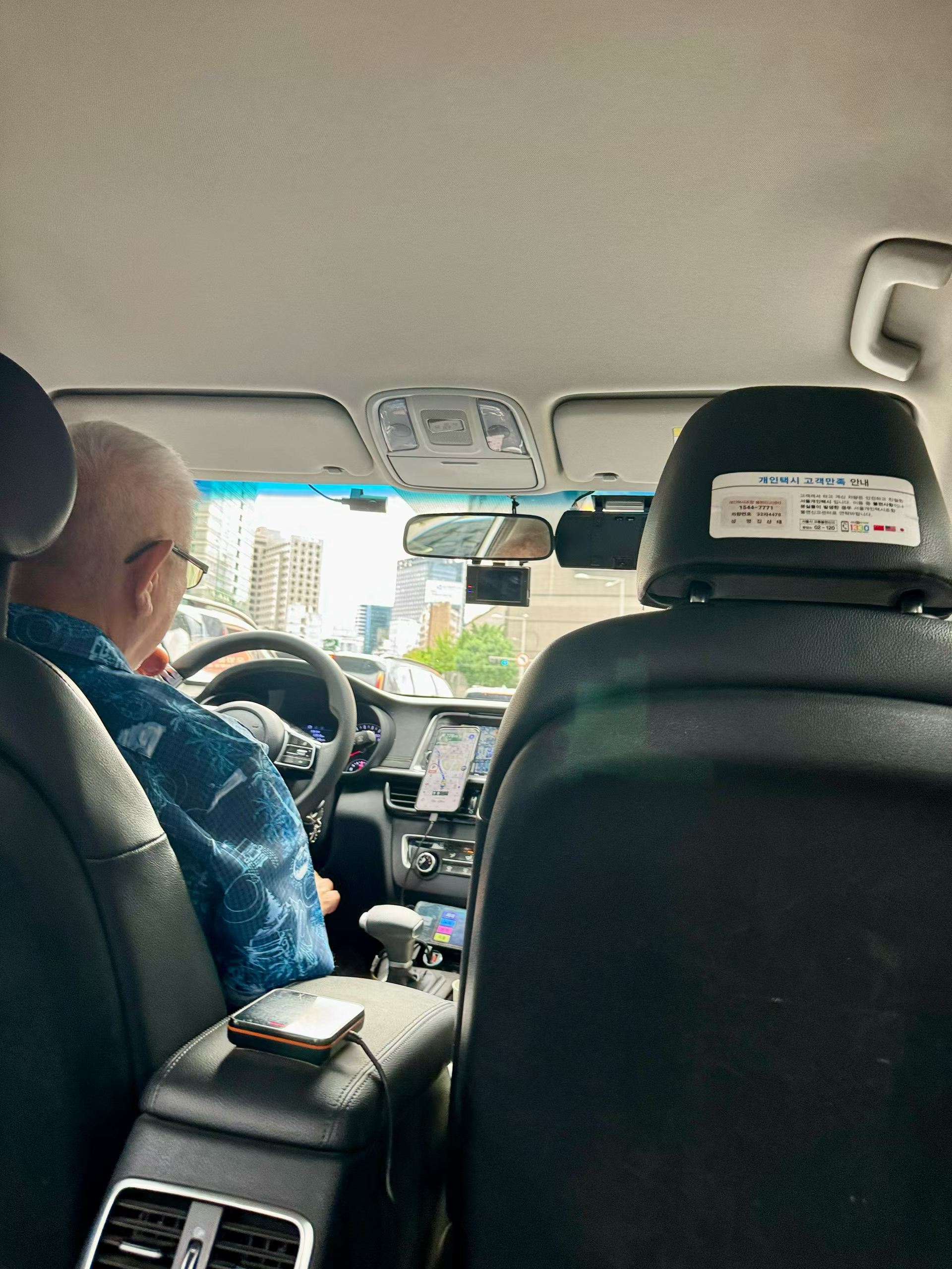 An older taxi driver seen from the rear seat in Greater Seoul